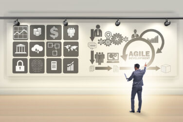A businessman in front of a wall that says Agile development along with various symbols related to business, money, computers, marketing, and more