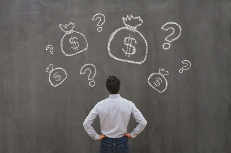 Man staring up at a wall with several drawings on bas with the dollar sign on them and question marks surrounding them