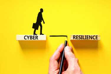 A silhouette of a man standing on a wooden plank that says Cyber with a hand drawing a line across a gap he can cross to another wooden plank that says Resilience