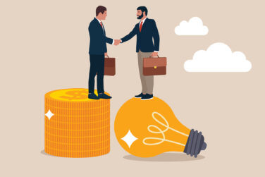 An illustration of two businessman holding briefcases and shaking hands. One is standing on a pile of neatly stacked coins and the other is standing on a light bulb.